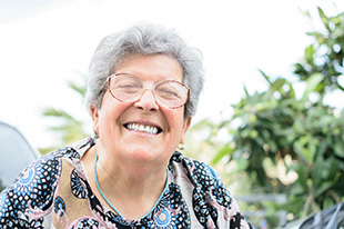 Senior woman with glasses smiling outside