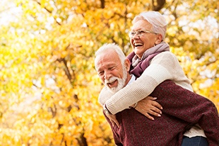 An older couple playing and laughing outside after learning the cost of dental implants in Deer Park and preparing for treatment 