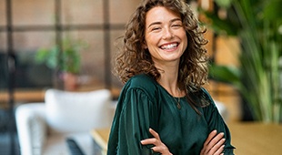 Woman in green shirt smiling with arms folded