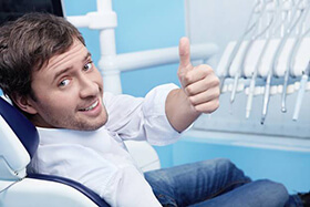 Smiling man in dental chair giving thumbs up