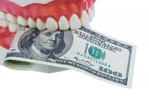 A denture holding a one hundred dollar bill.