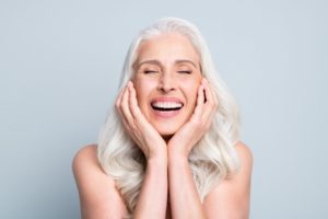 a woman smiling happily with her long-lasting dental implants