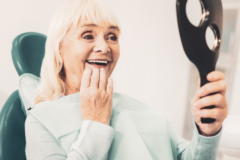 A smiling woman admiring her new dentures