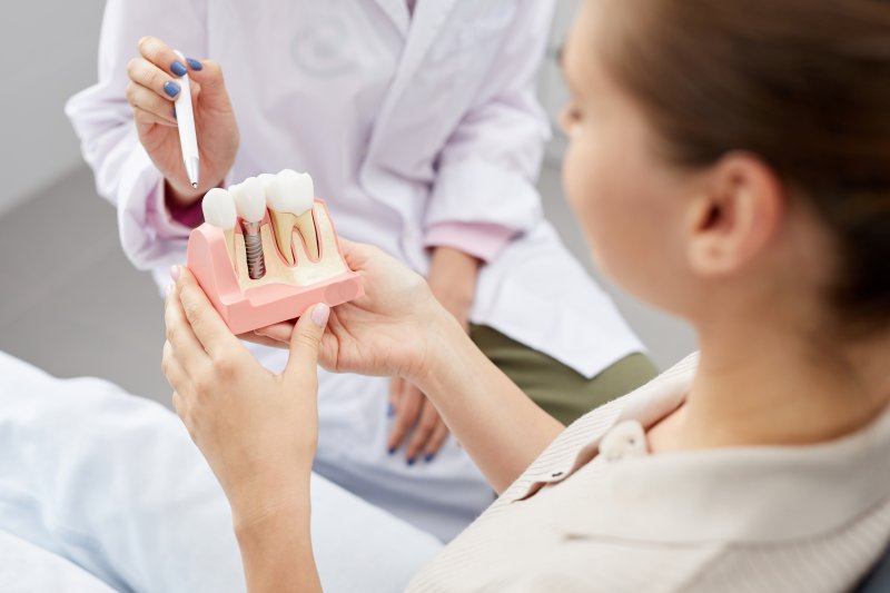 A patient holding an enlarged model of a dental implant